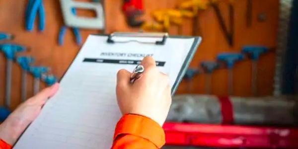 A supervisor is writing on paper form during perform inventory checklist of working tool and equipment (blurred background)